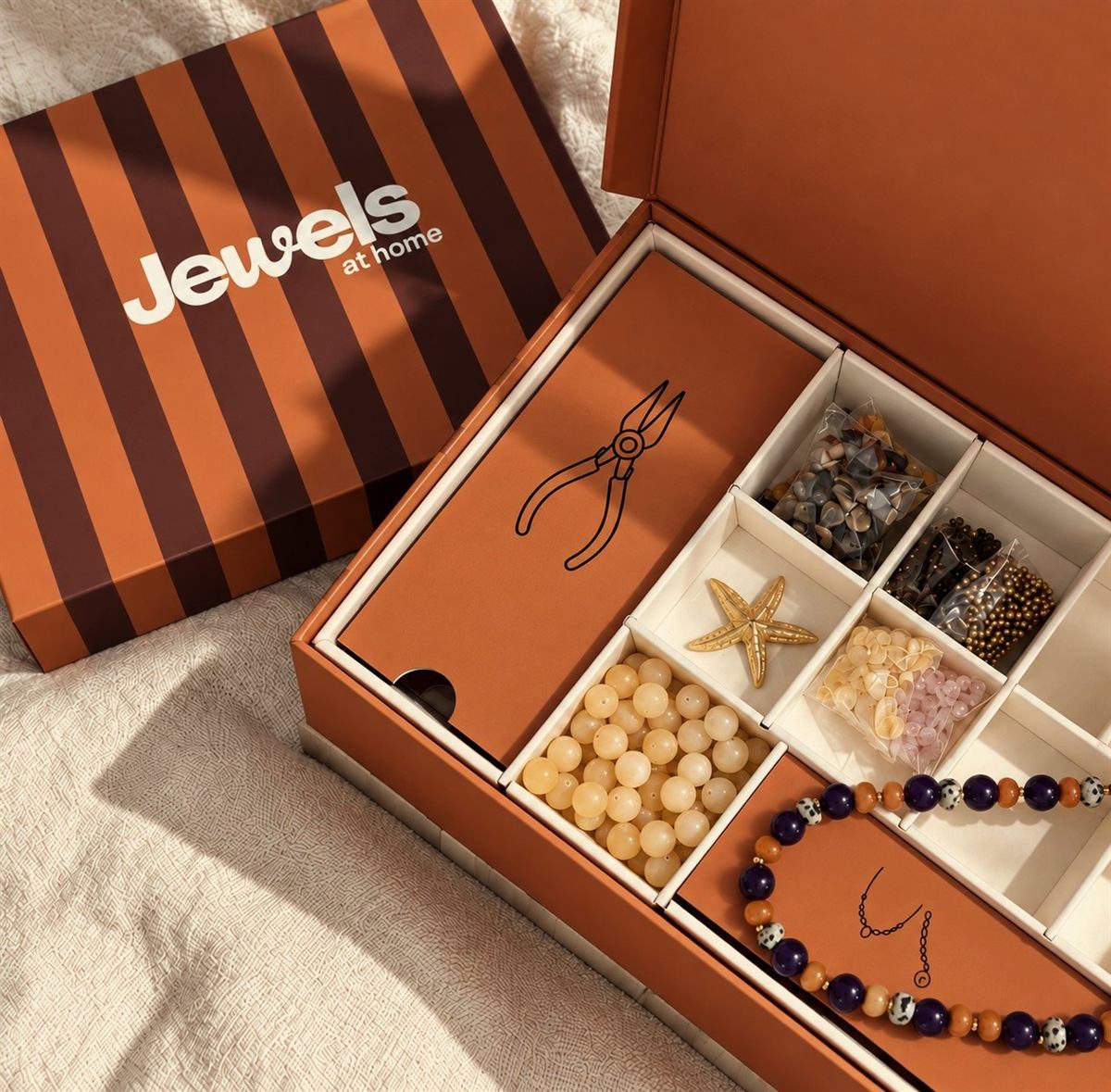 La caja JEWELSathome abierta con las piedras, los charms y los alicates